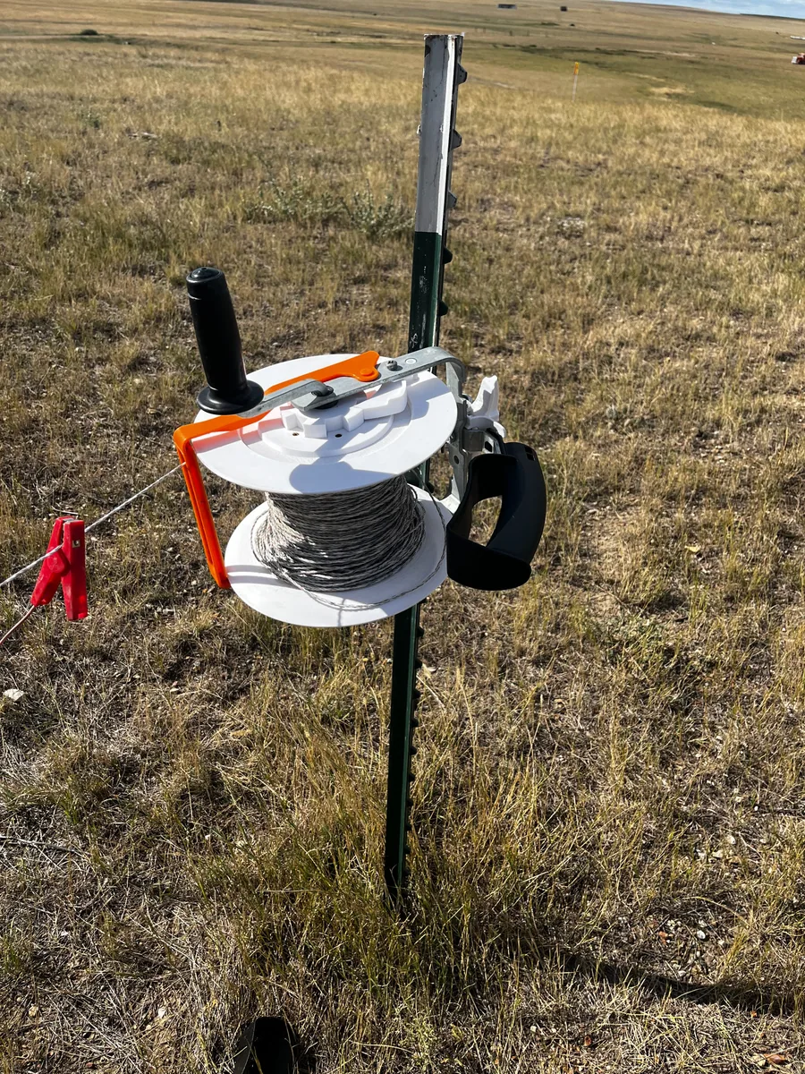 White and orange replacement reel components installed on a fence reel in the field